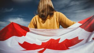A young girl proudly holding a Canadian flag for Canadian Immigration success