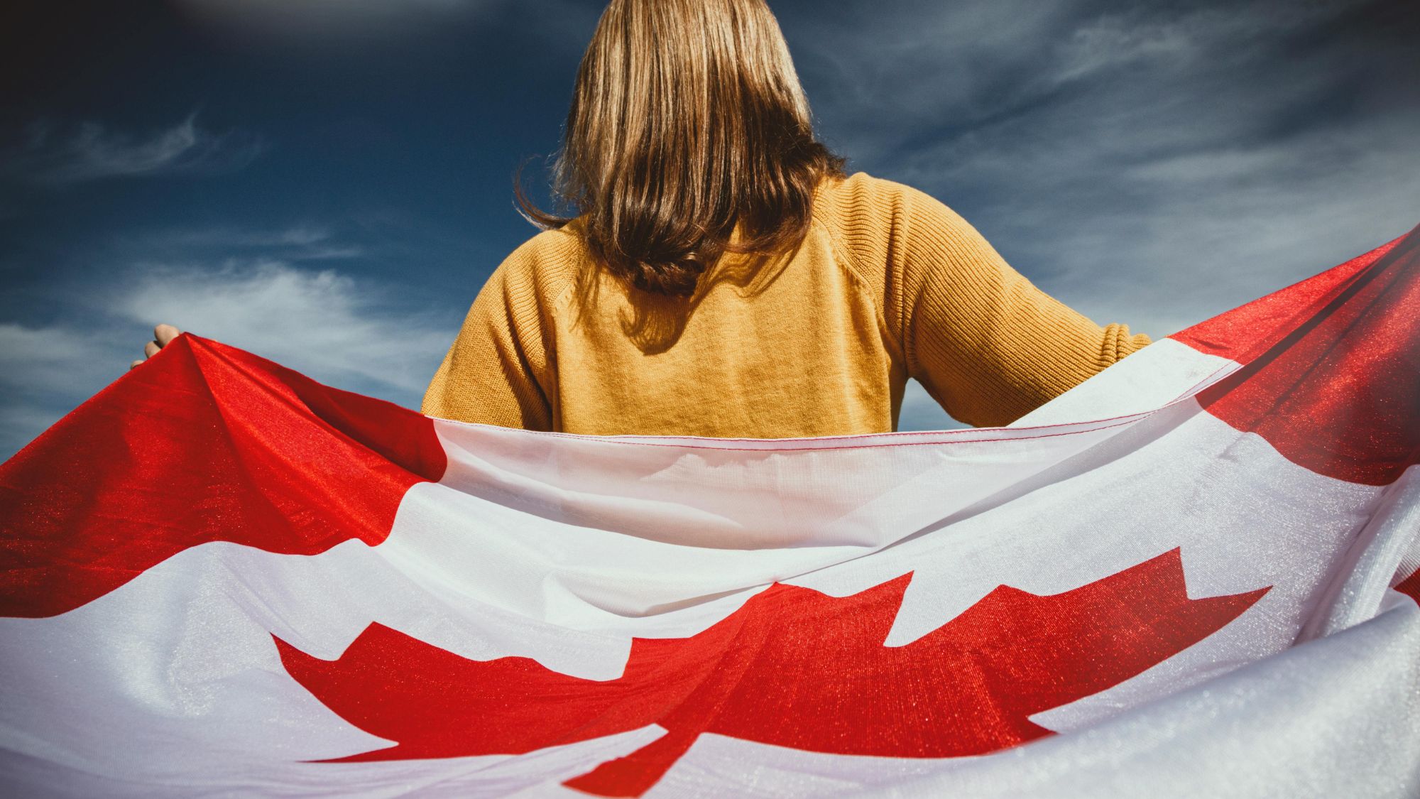 A young girl proudly holding a Canadian flag for Canadian Immigration success